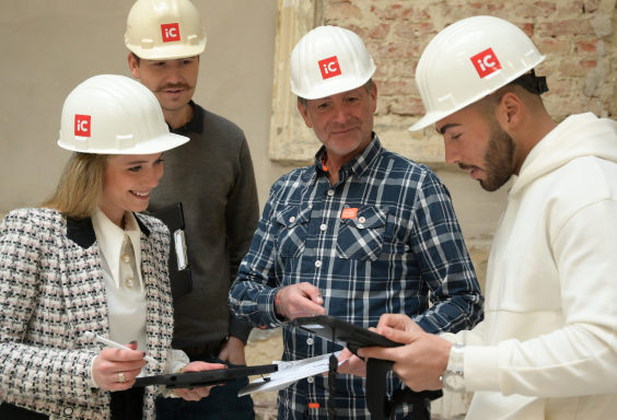 Four iC project managers wearing construction helmets in a meeting